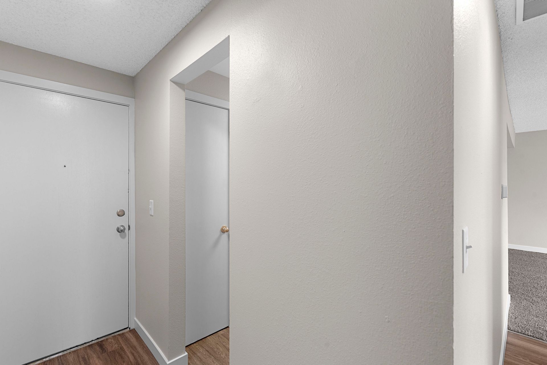 A hallway with a white door and a white wall.