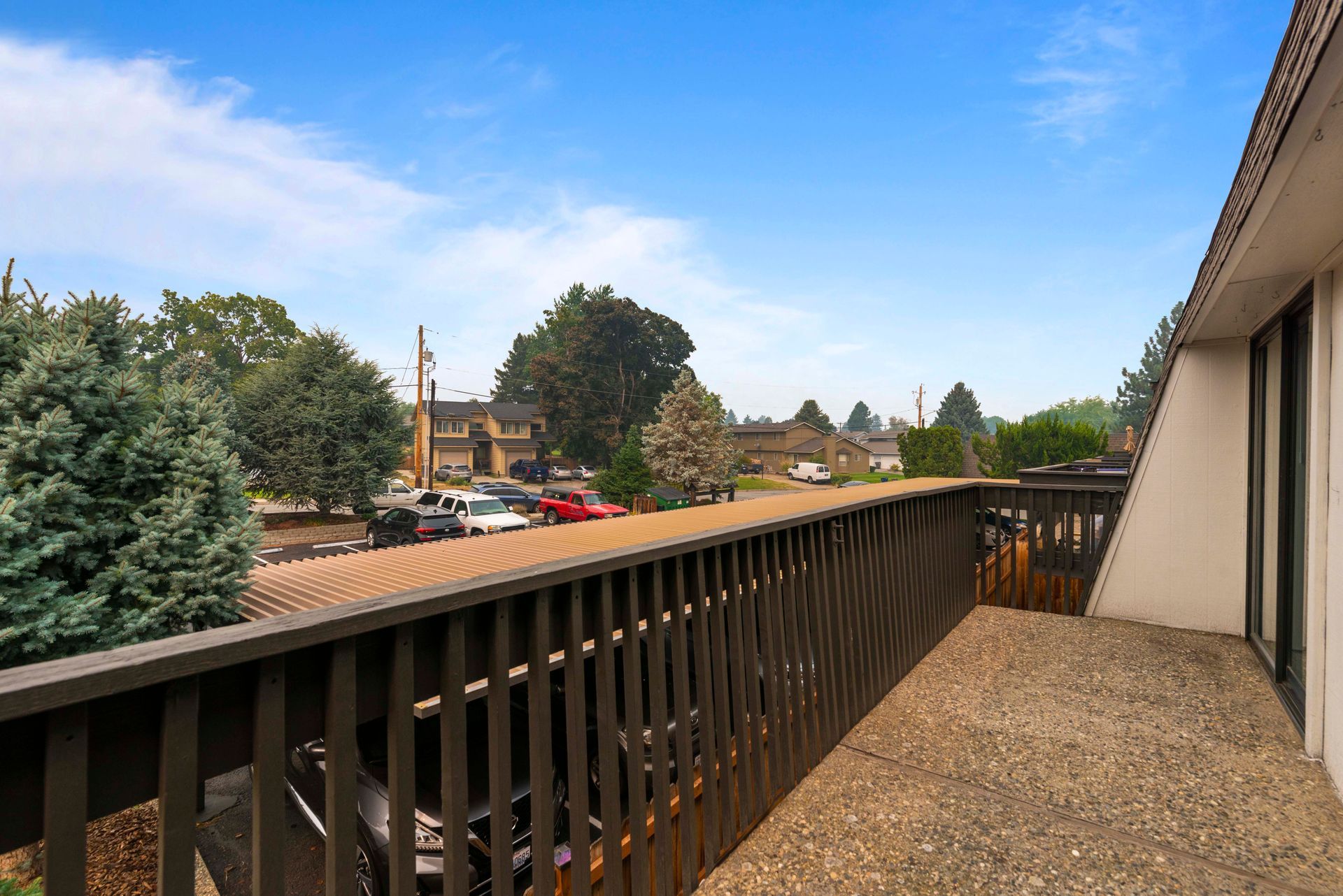 A balcony with a fence and a view of a parking lot.