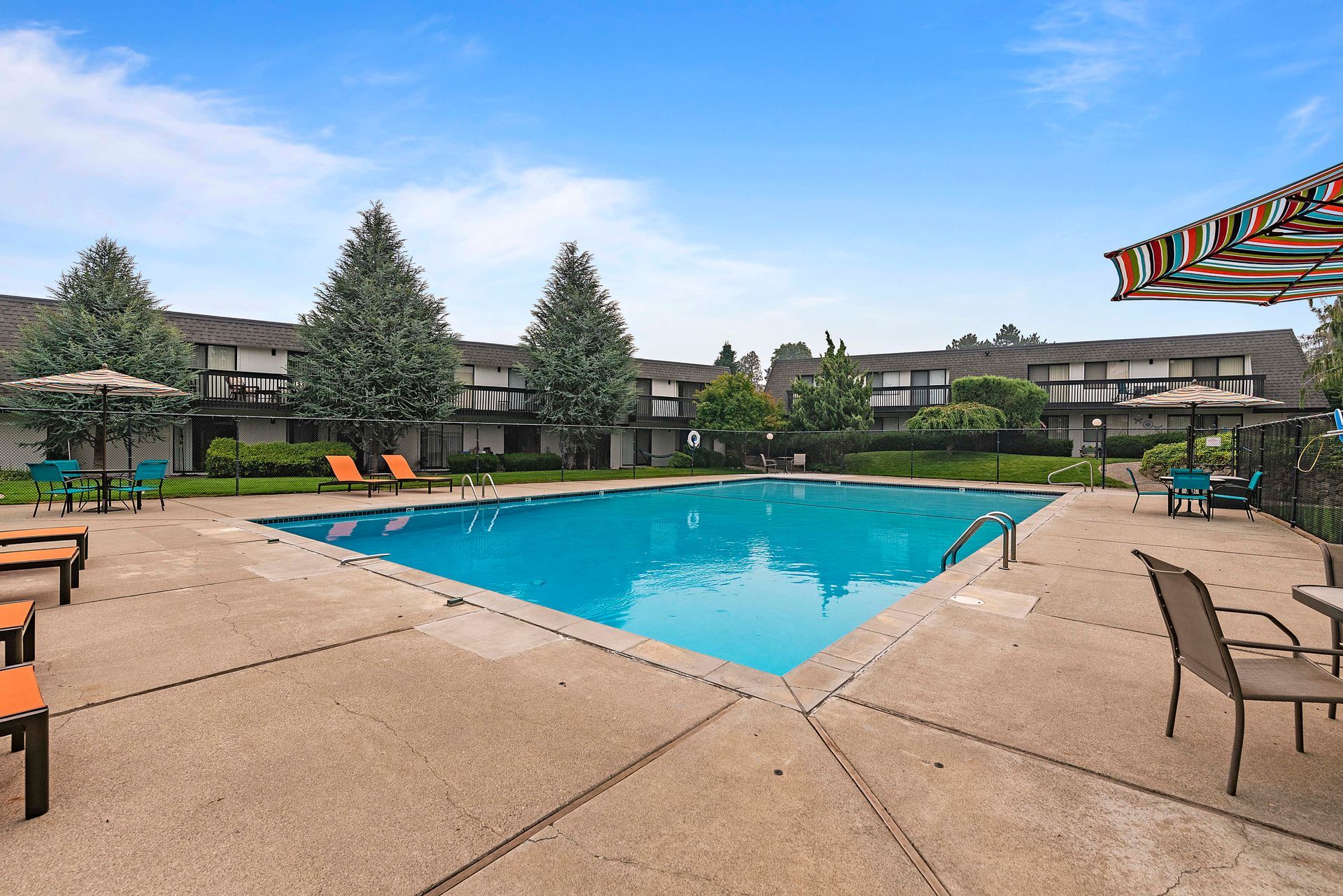 A large swimming pool with chairs and umbrellas in front of a building.