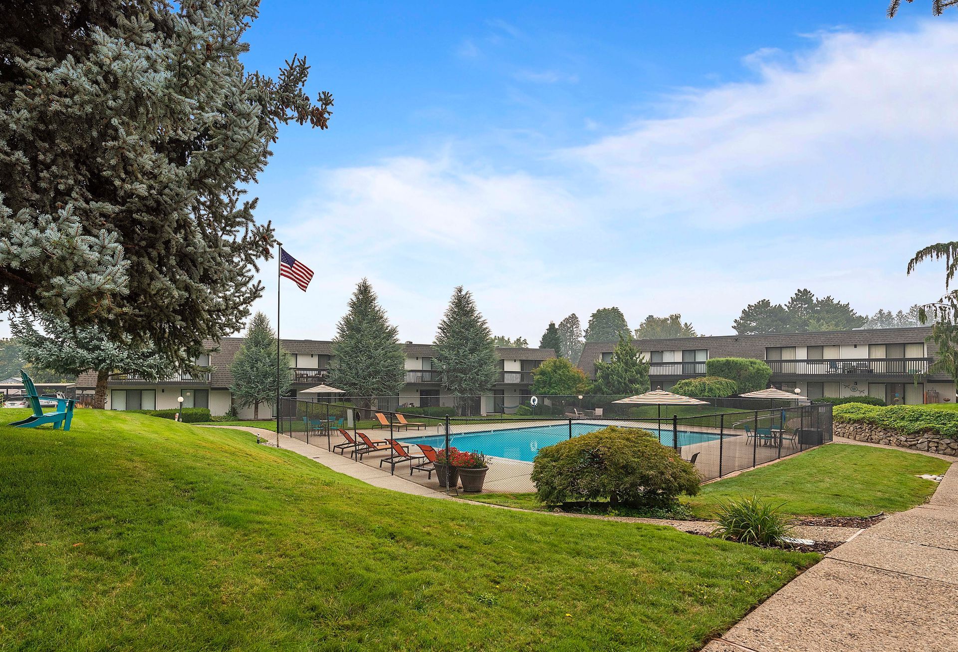 There is a large swimming pool in the middle of a lush green field.