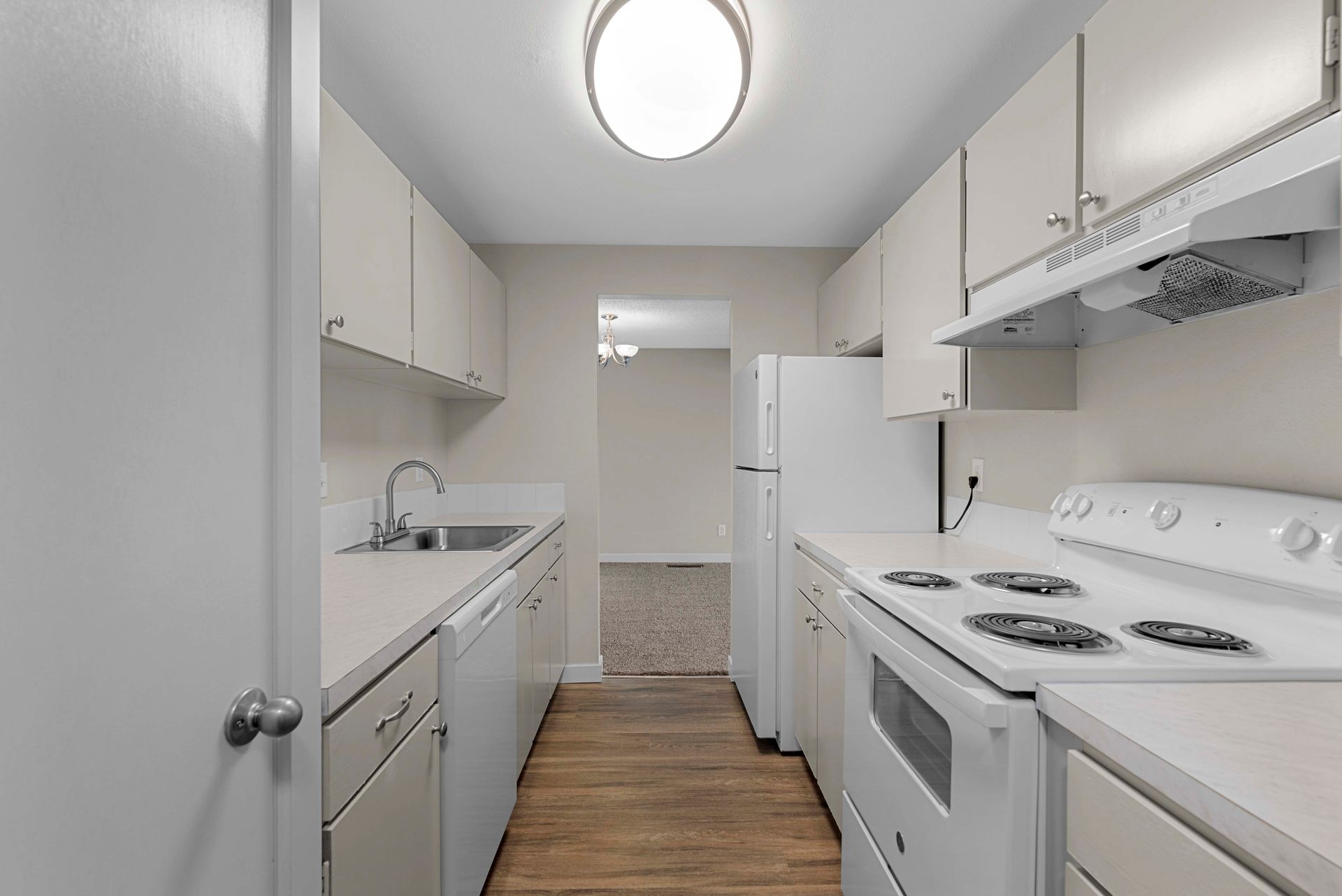 A kitchen with white cabinets , a stove , a refrigerator , and a sink.