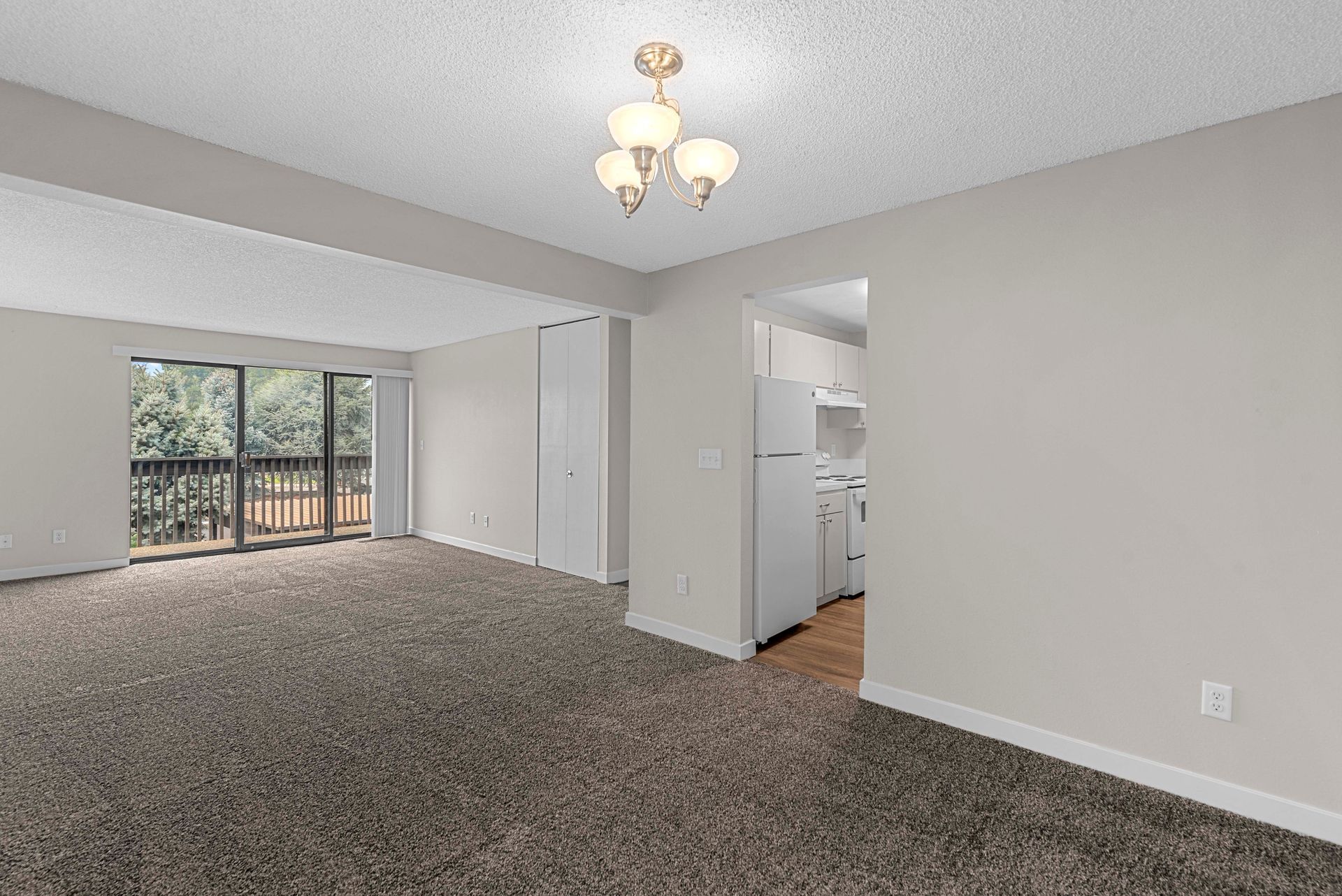 An empty living room with a balcony and a chandelier.