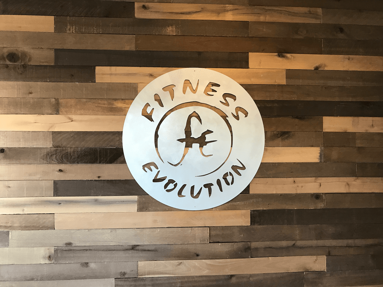 A sign on a wooden wall that says fitness evolution
