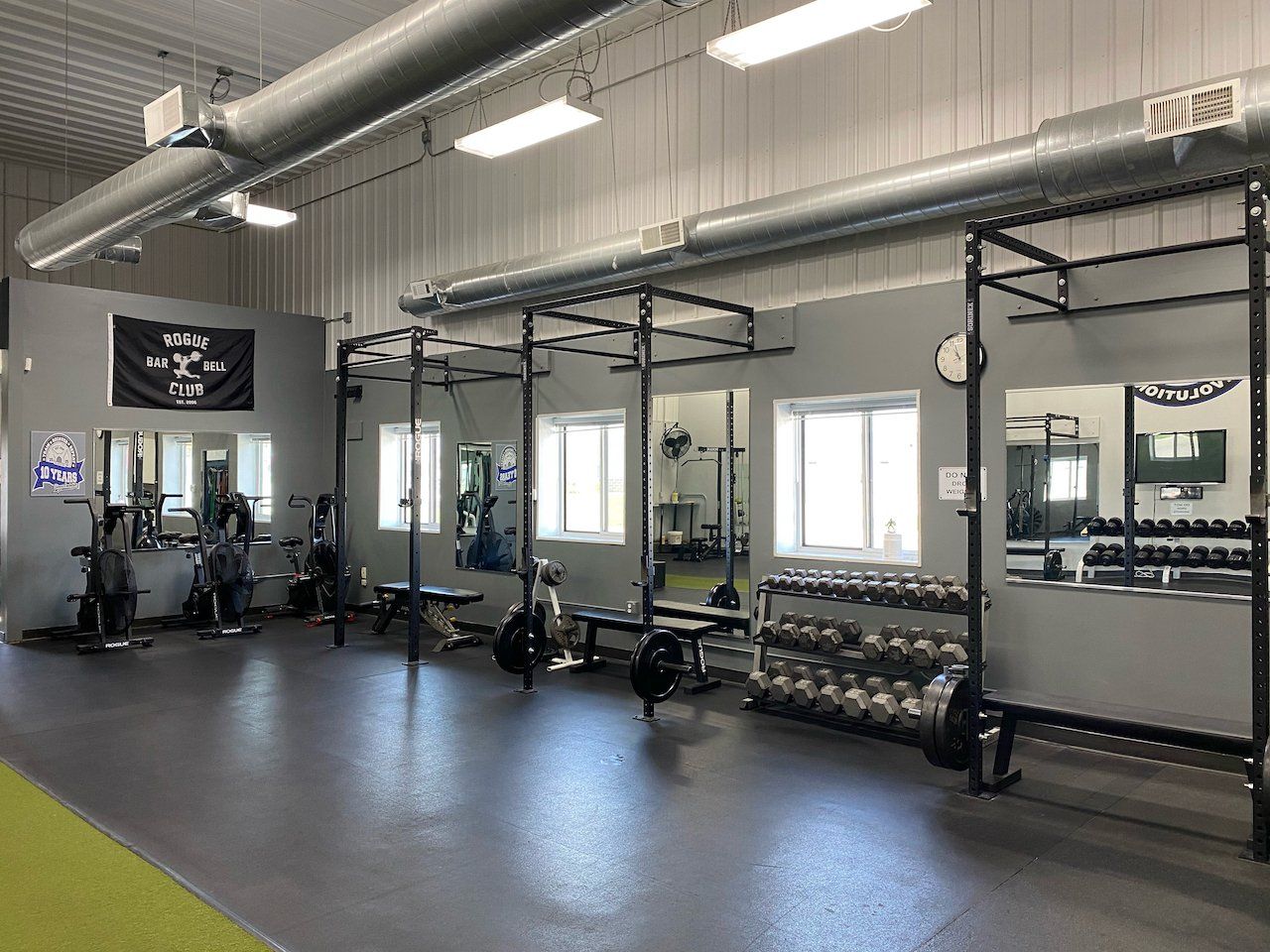 A gym with a lot of exercise equipment and a lot of windows.