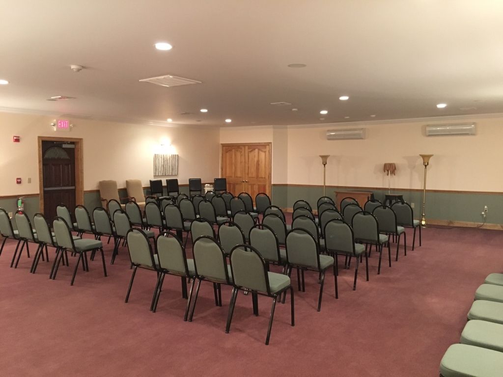 Rows of chairs in a carpeted room, likely for a gathering.  Neutral-colored walls and doors.