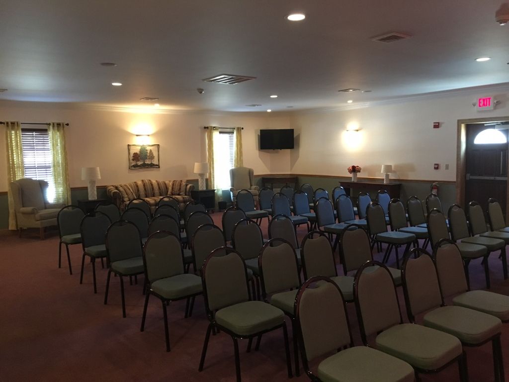 Rows of chairs face a sofa and a small stage area in a room.
