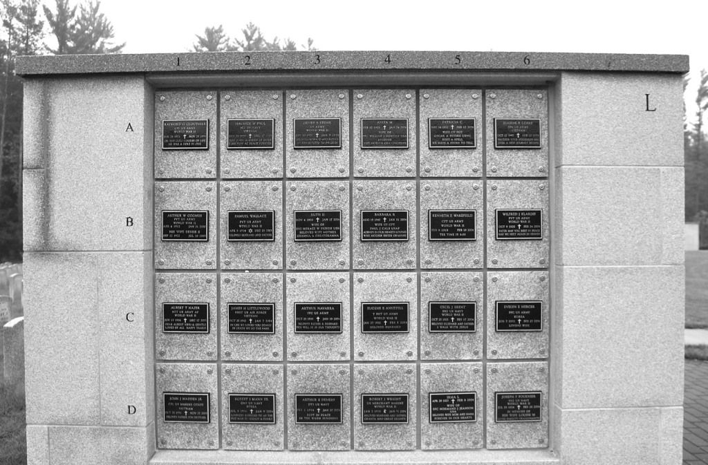 Columbarium wall with rectangular niches holding plaques, in a cemetery.