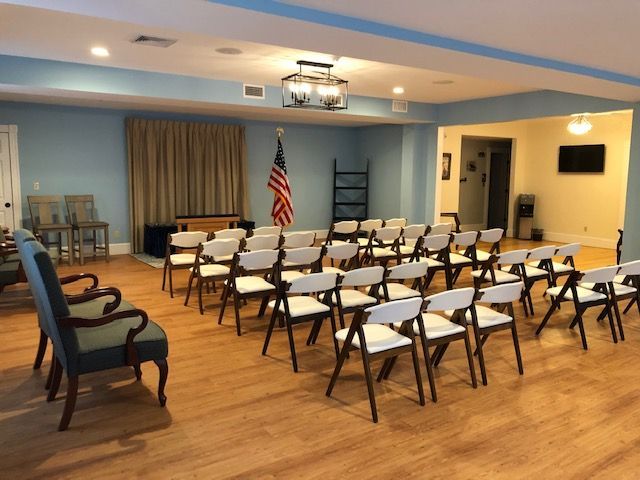 A room arranged with rows of chairs, American flag, and a closed curtain.