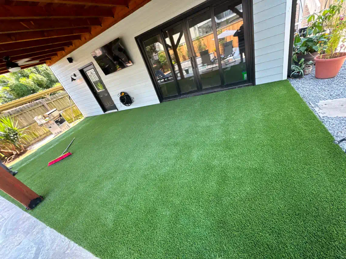 A patio with a lot of green grass and a house in the background.