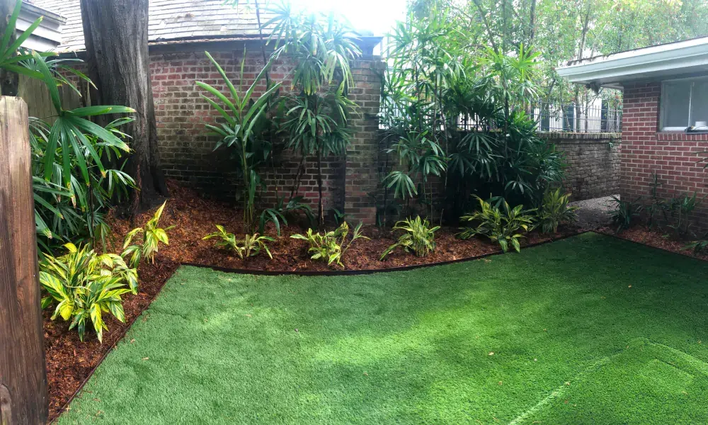 A backyard with a lush green lawn and a brick wall.