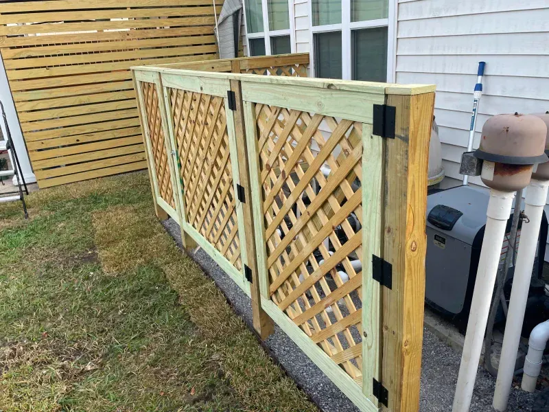 A wooden fence with a lattice design is in the backyard of a house.