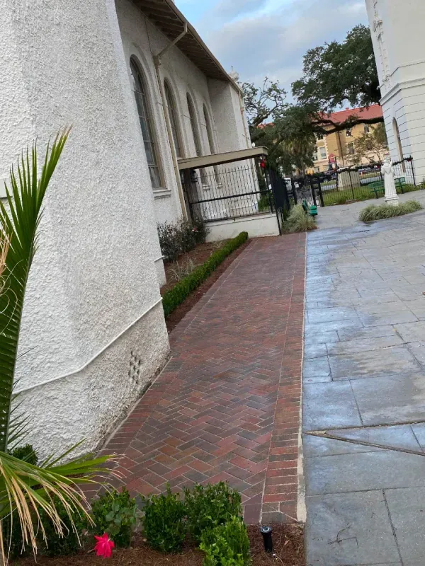 A brick walkway leading to a white building