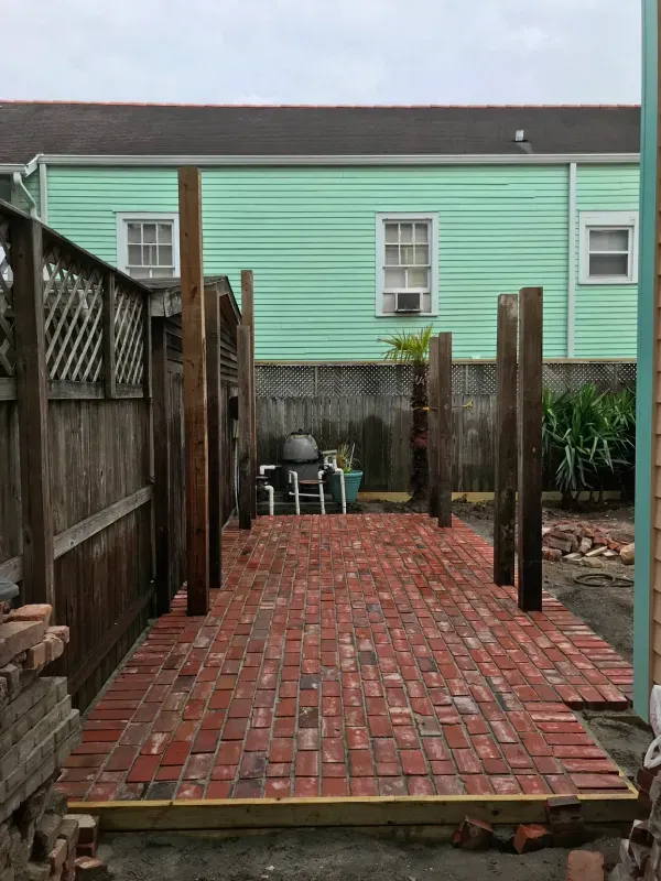 A brick walkway is being built in front of a green house.