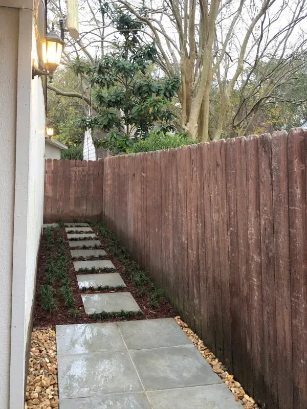 A walkway leading to a house with a wooden fence.