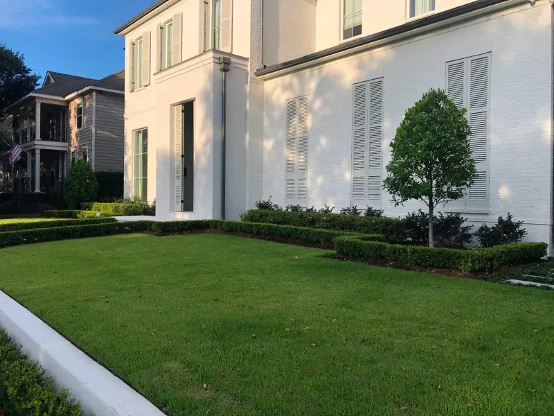 A large white house with a lush green lawn in front of it