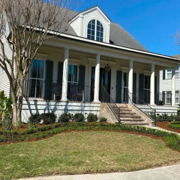 A white house with black shutters and a large porch