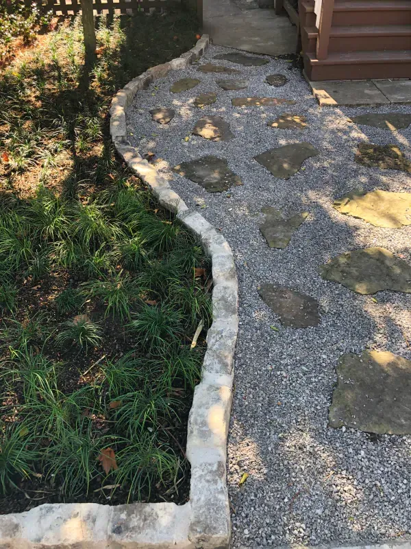 A stone walkway leading to a house with gravel and rocks.