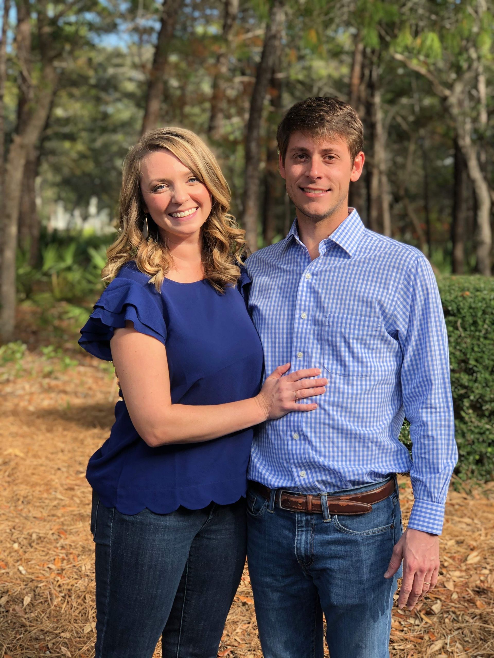 A fire pit in the backyard of a house with a wooden cross in the background.