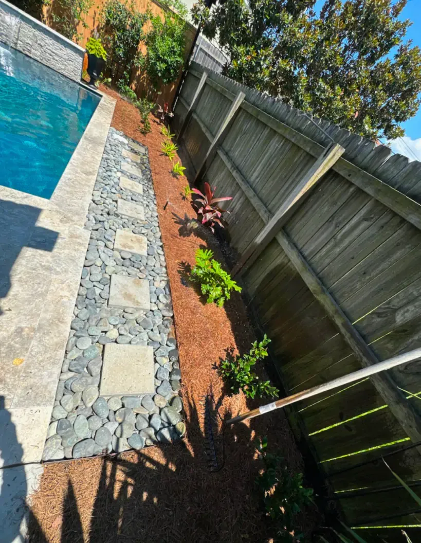 A wooden fence surrounds a swimming pool in a backyard.