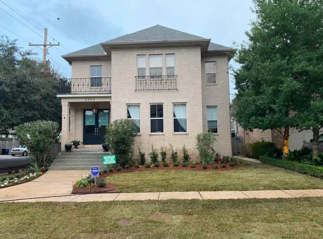 A large brick house with a large lawn in front of it.