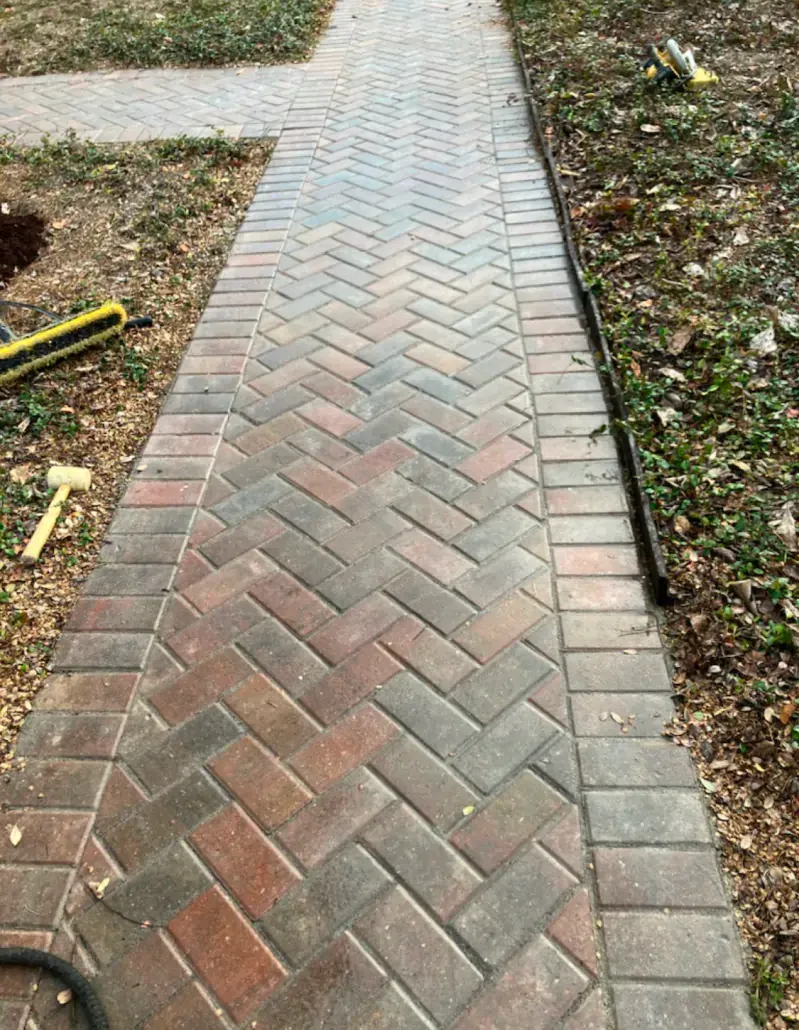 A brick walkway with a herringbone pattern is being built.