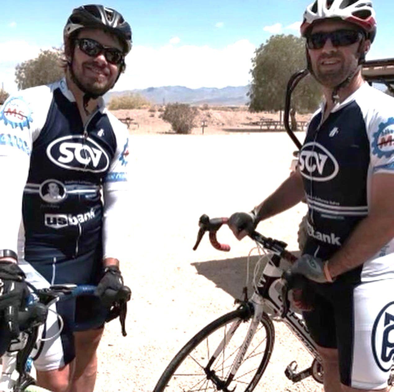 Adam and Matt Bullard riding their back and wearing black and white cycling uniform