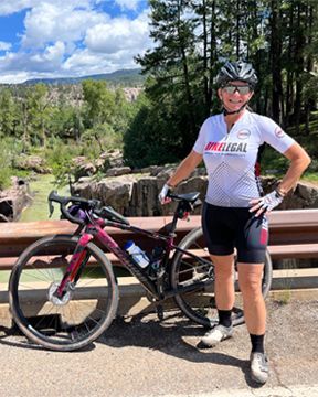 Mila Allinson, standing next to her bike, leaned against a bridge railing in Colorado.