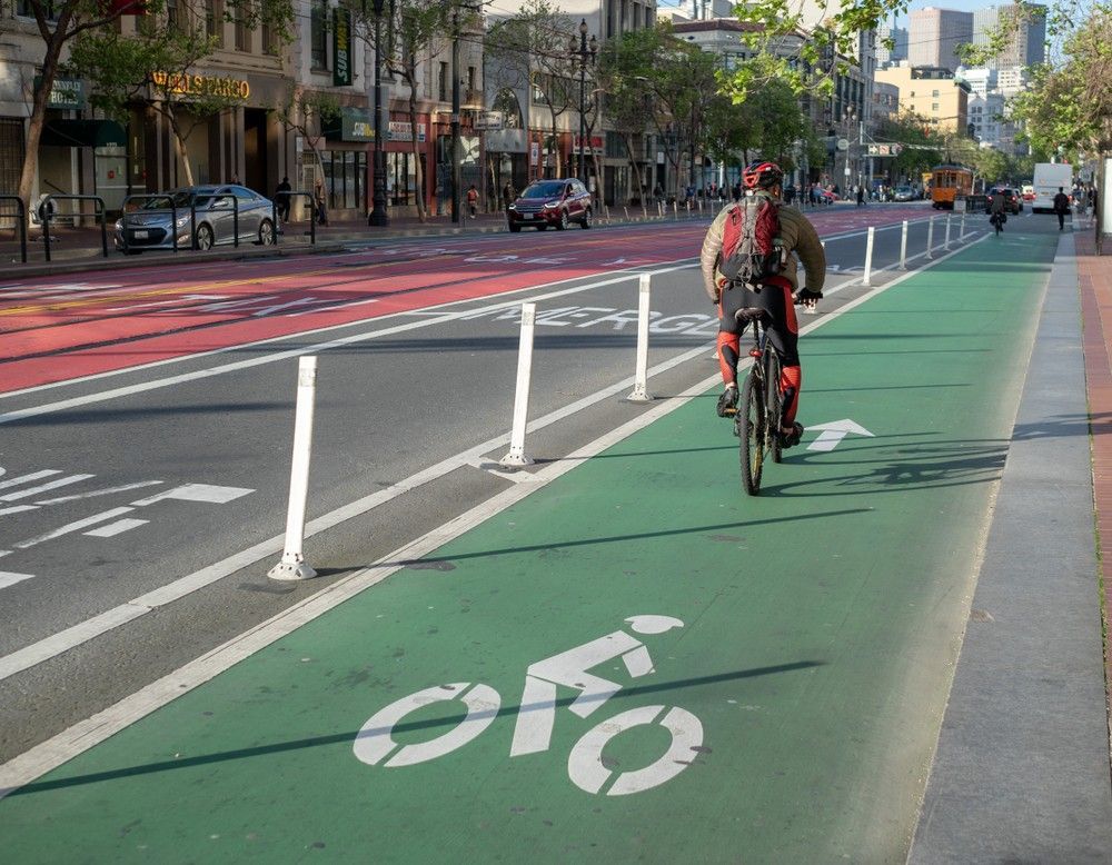 Cyclist riding on a protected bicycle lane in San Francisco. California Bike Lanes and Bicycle Infra