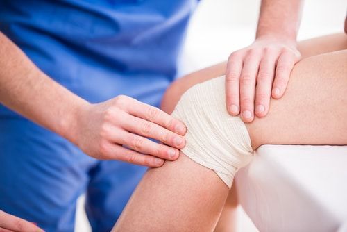 Doctor is rewinding knee bandage to young woman
