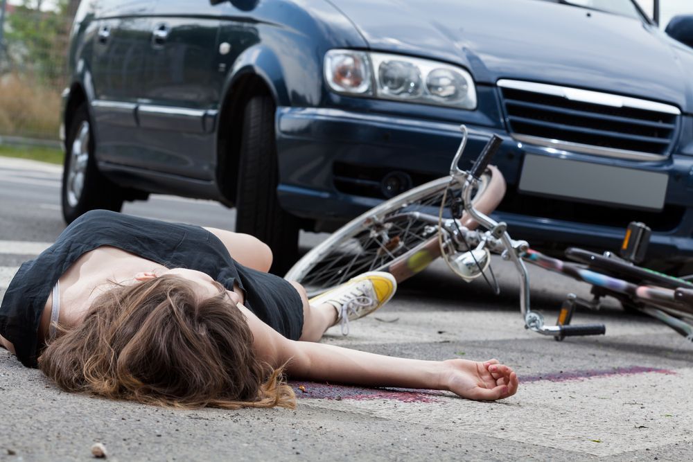 female cyclist in laying in roadway with head injury