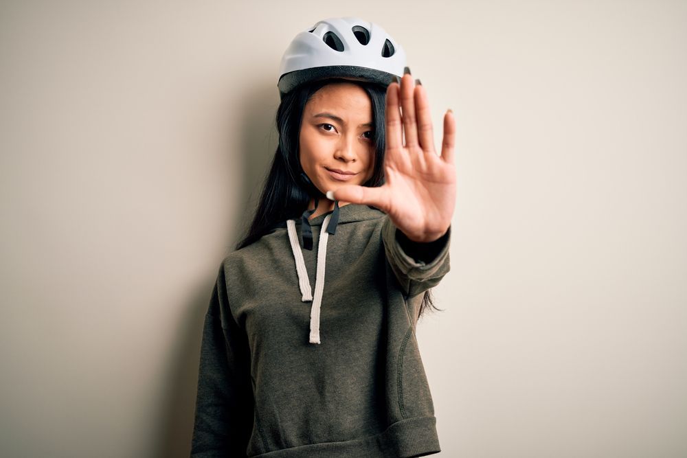 girl wearing bicycle helmet motioning to stop