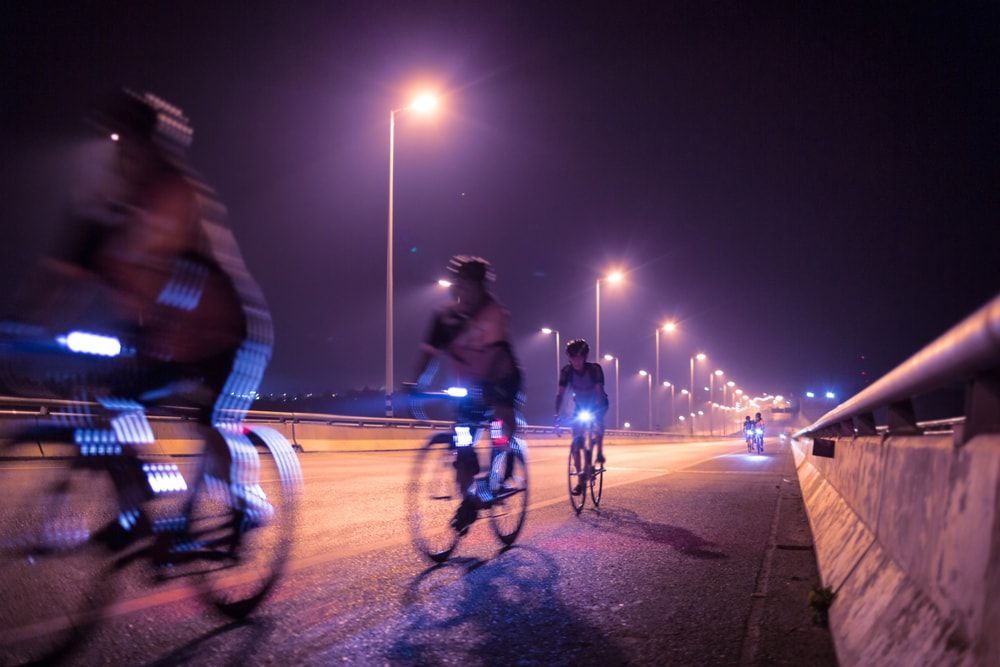 Group of cyclists at night on a bridge with front headlights