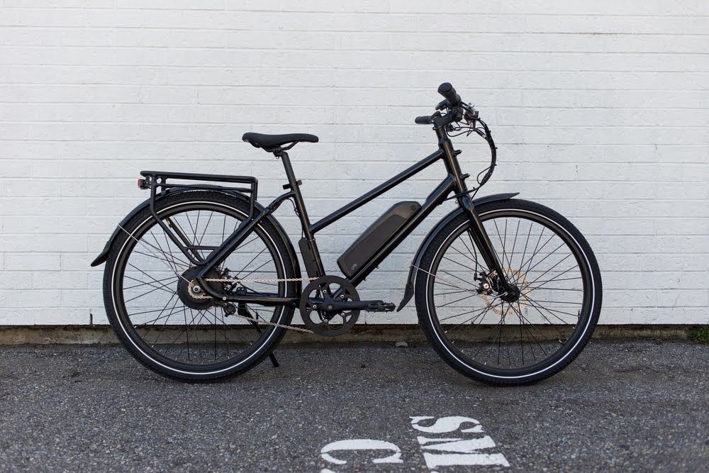 Modern black electric bicycle against white brick wall