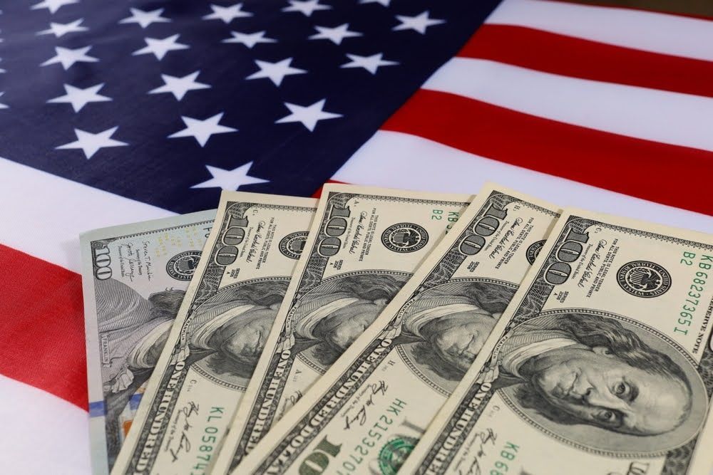 one hundred dollar bills on an American flag background, money funding for e-bike tax credits and rebates
