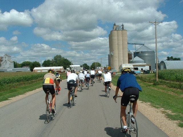 RAGBRAI group of cyclists on an Iowa road approaching a farm town