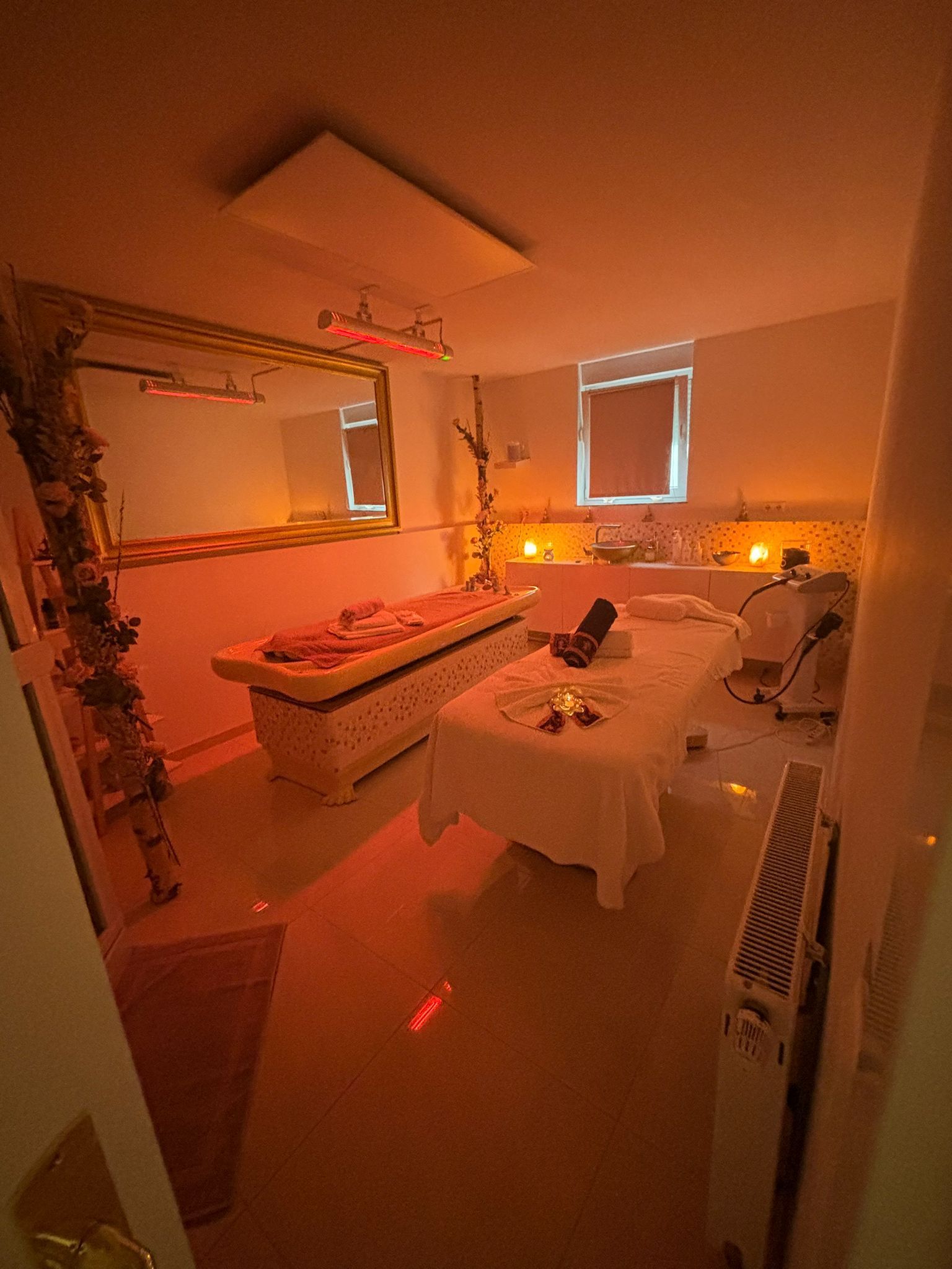 Ein Raum mit zwei Massagetischen und einem Spiegel.
