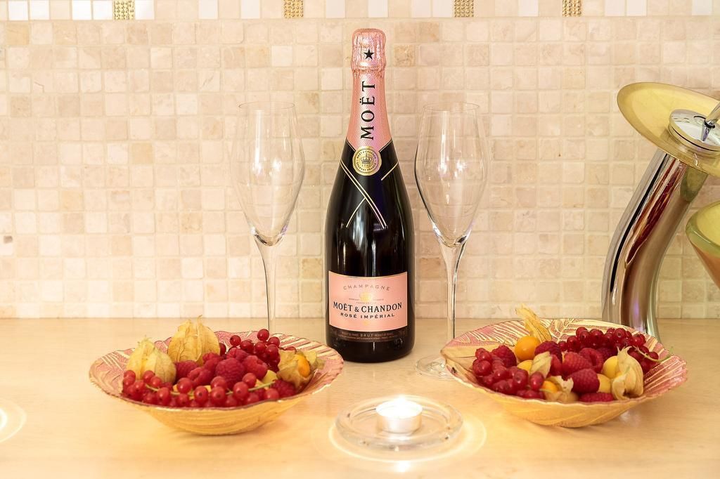 Zwei Schalen mit Himbeeren und eine Flasche Champagner auf einem Tisch