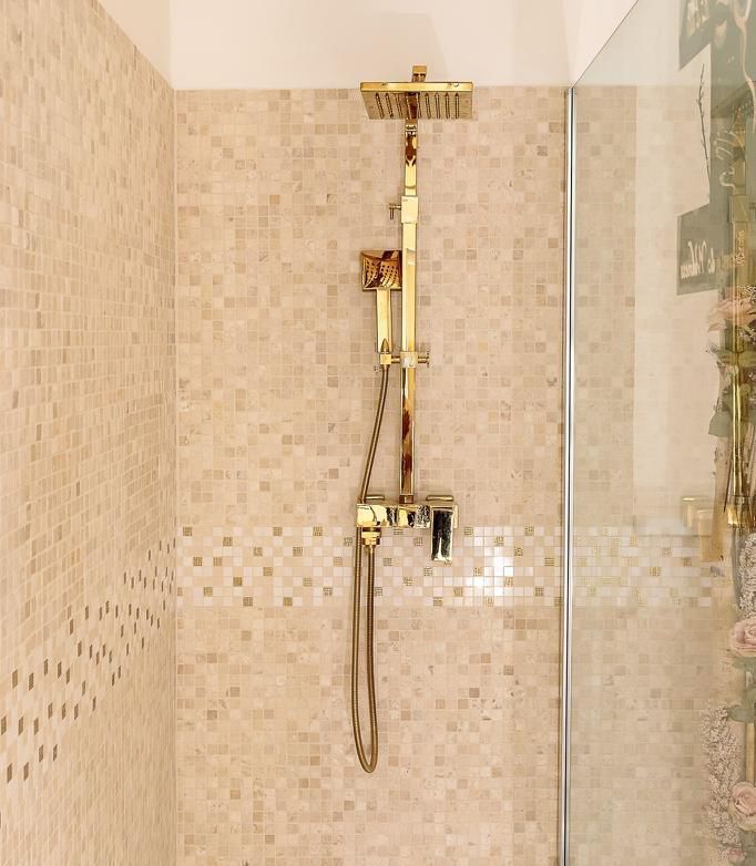 Eine Dusche mit goldenem Duschkopf und Glastür.