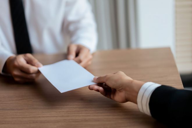 A man is handing a piece of paper to another man.