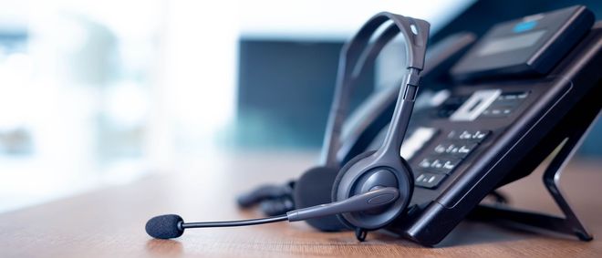 A telephone with a headset attached to it is sitting on a wooden table.