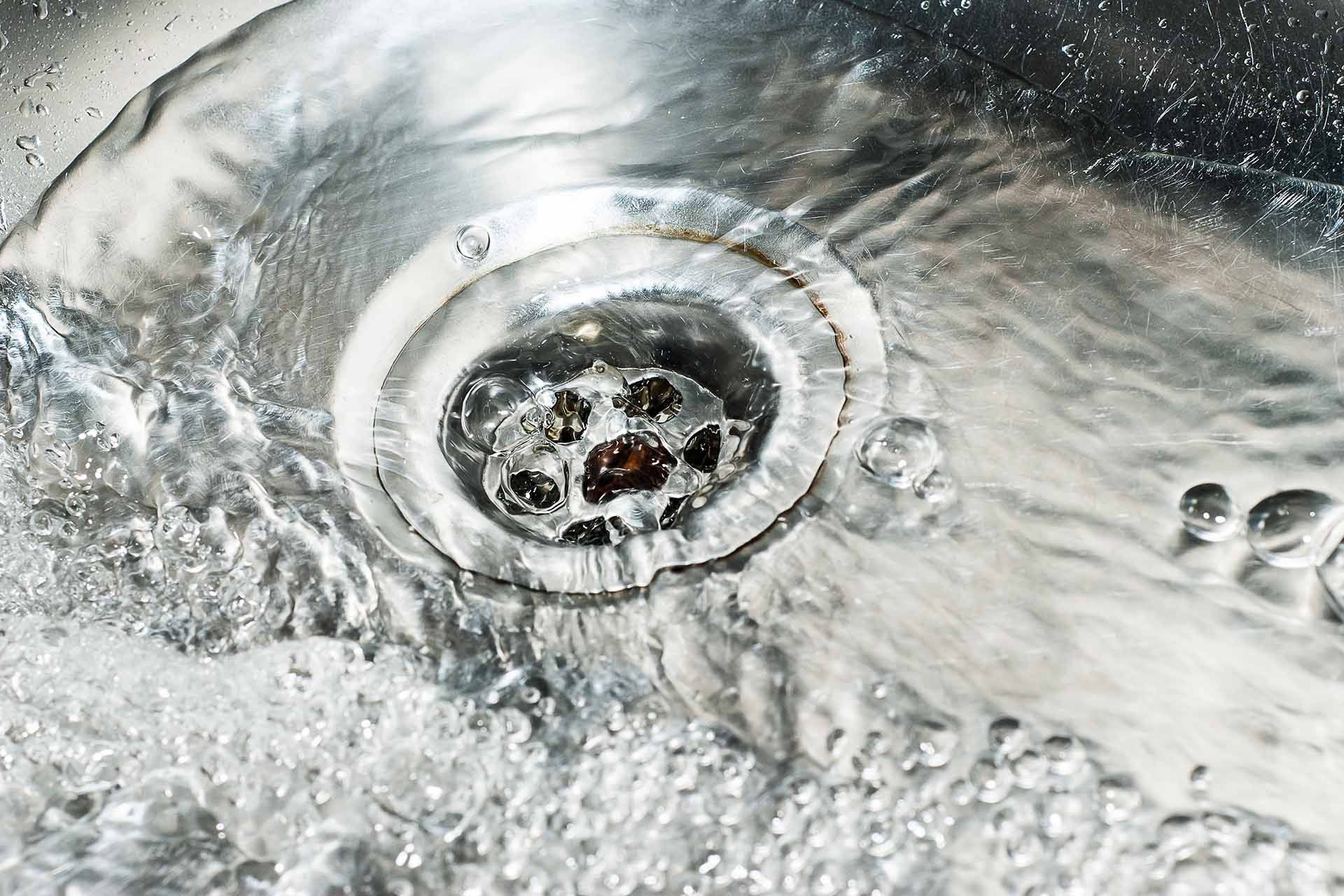 Water swirling down a stainless steel sink drain.