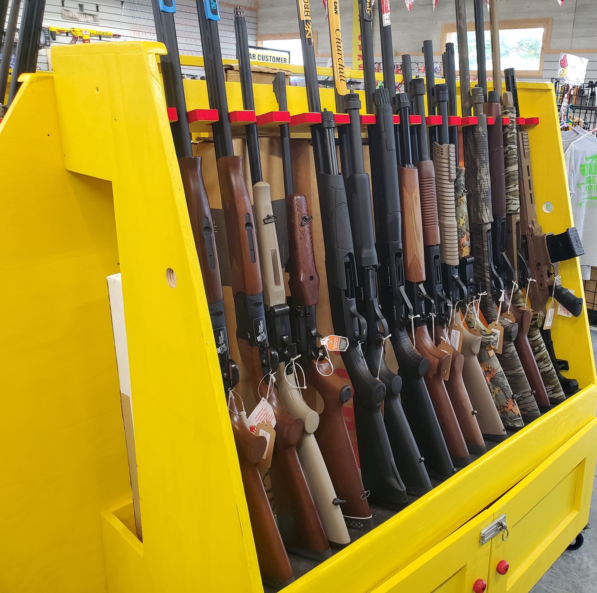 Yellow gun rack displaying rifles for sale.