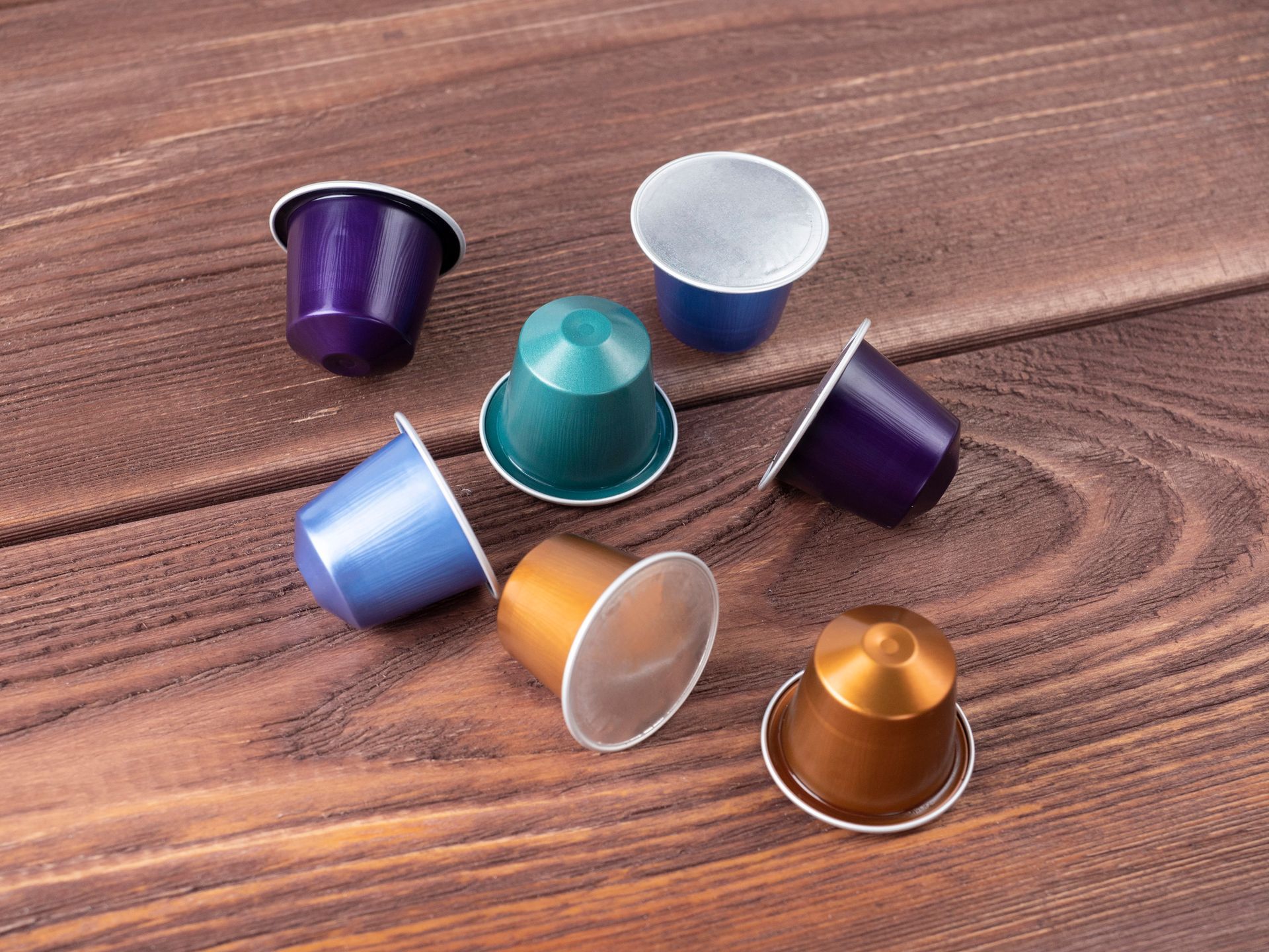 Capsule di caffè di vari colori su una superficie di legno.