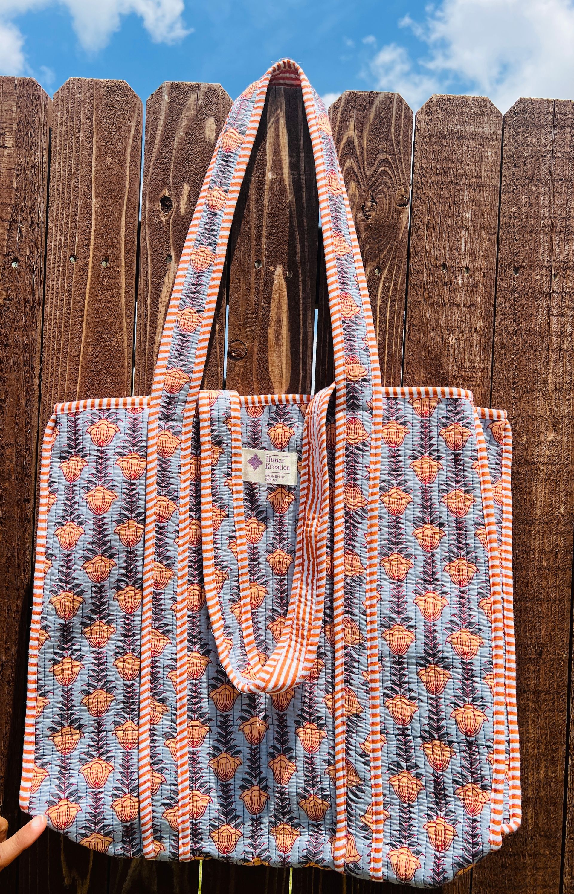 A tote bag is hanging on a wooden fence