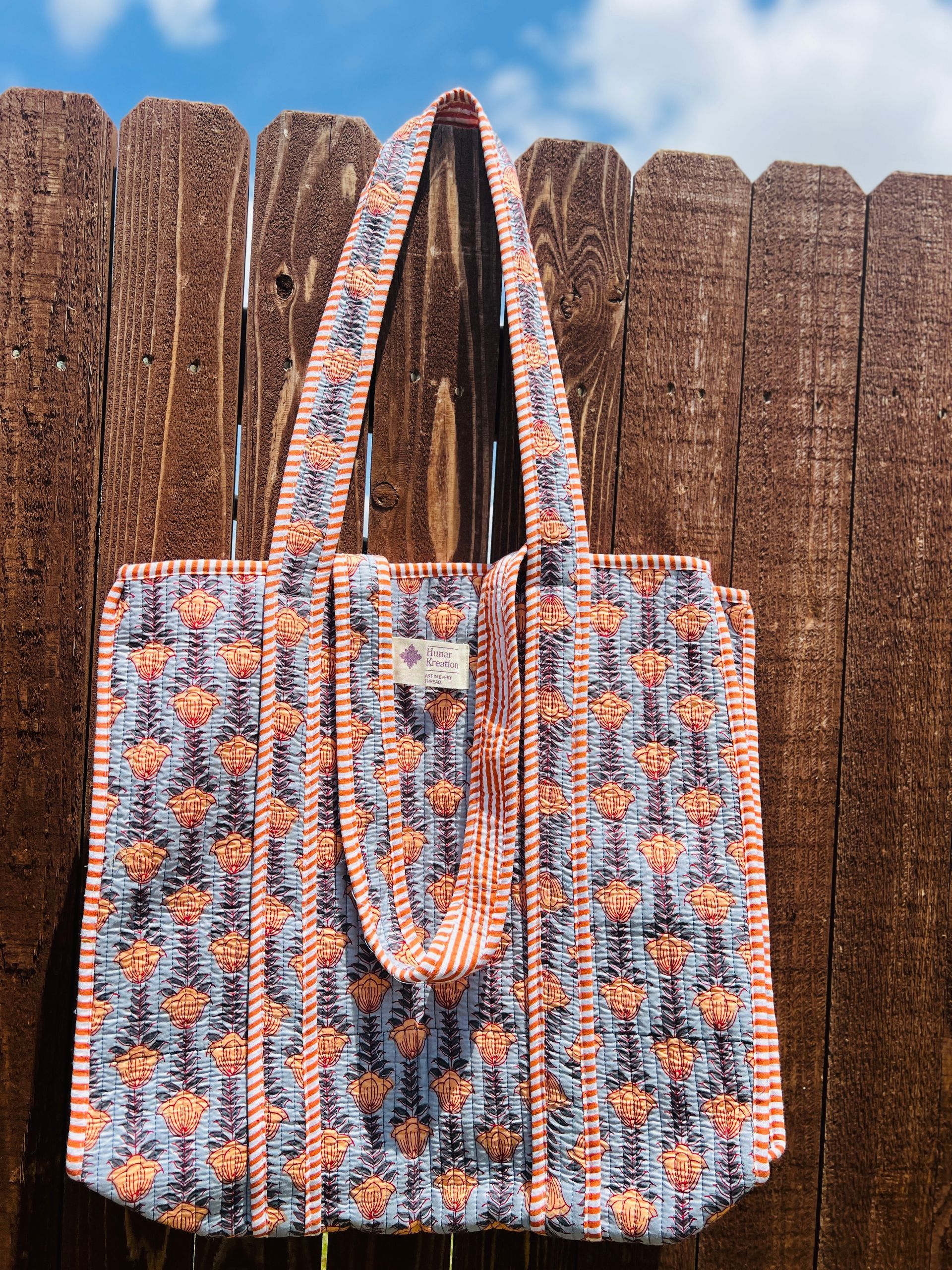 A tote bag is hanging on a wooden fence