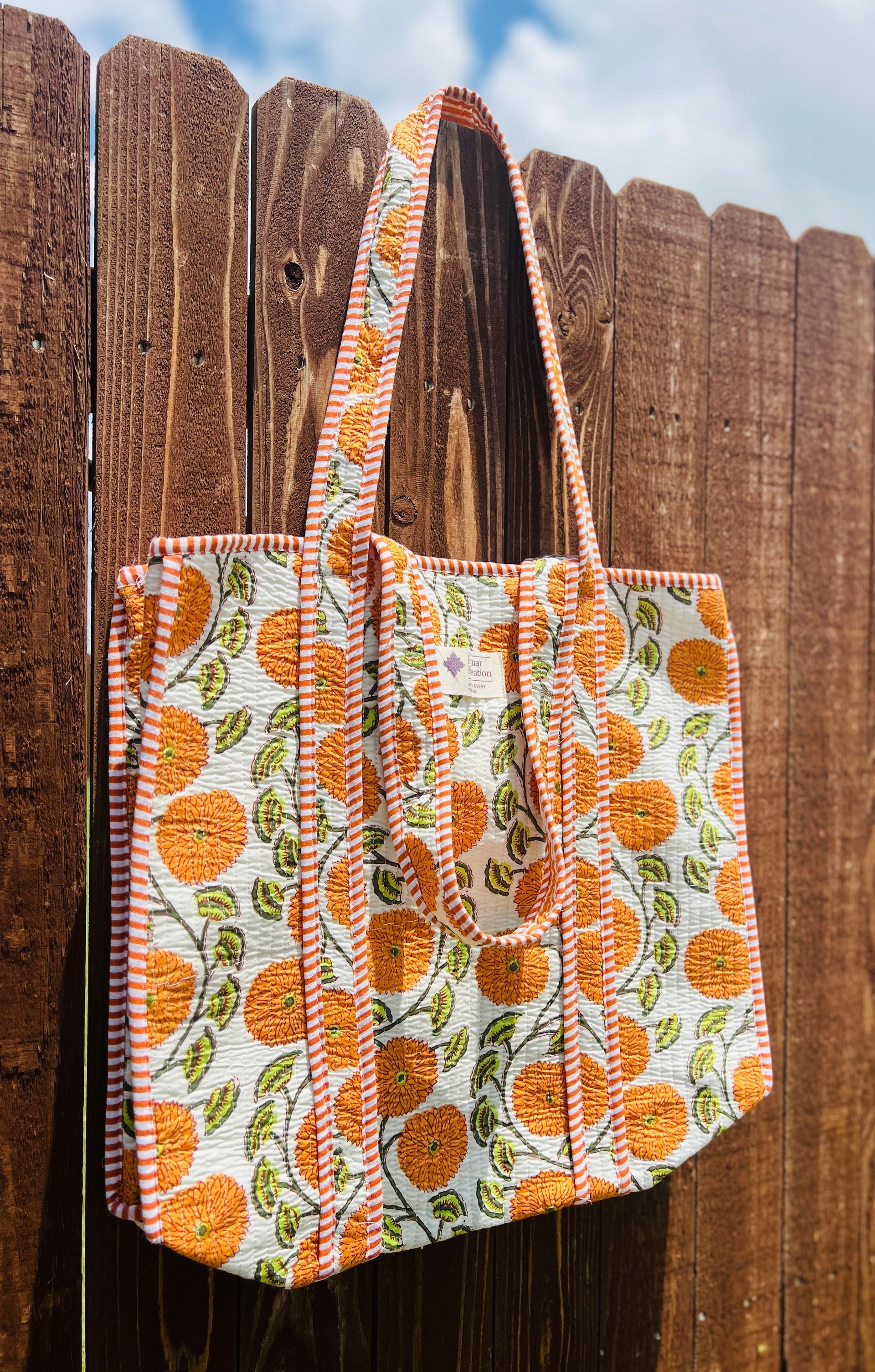 A tote bag is hanging on a wooden fence.