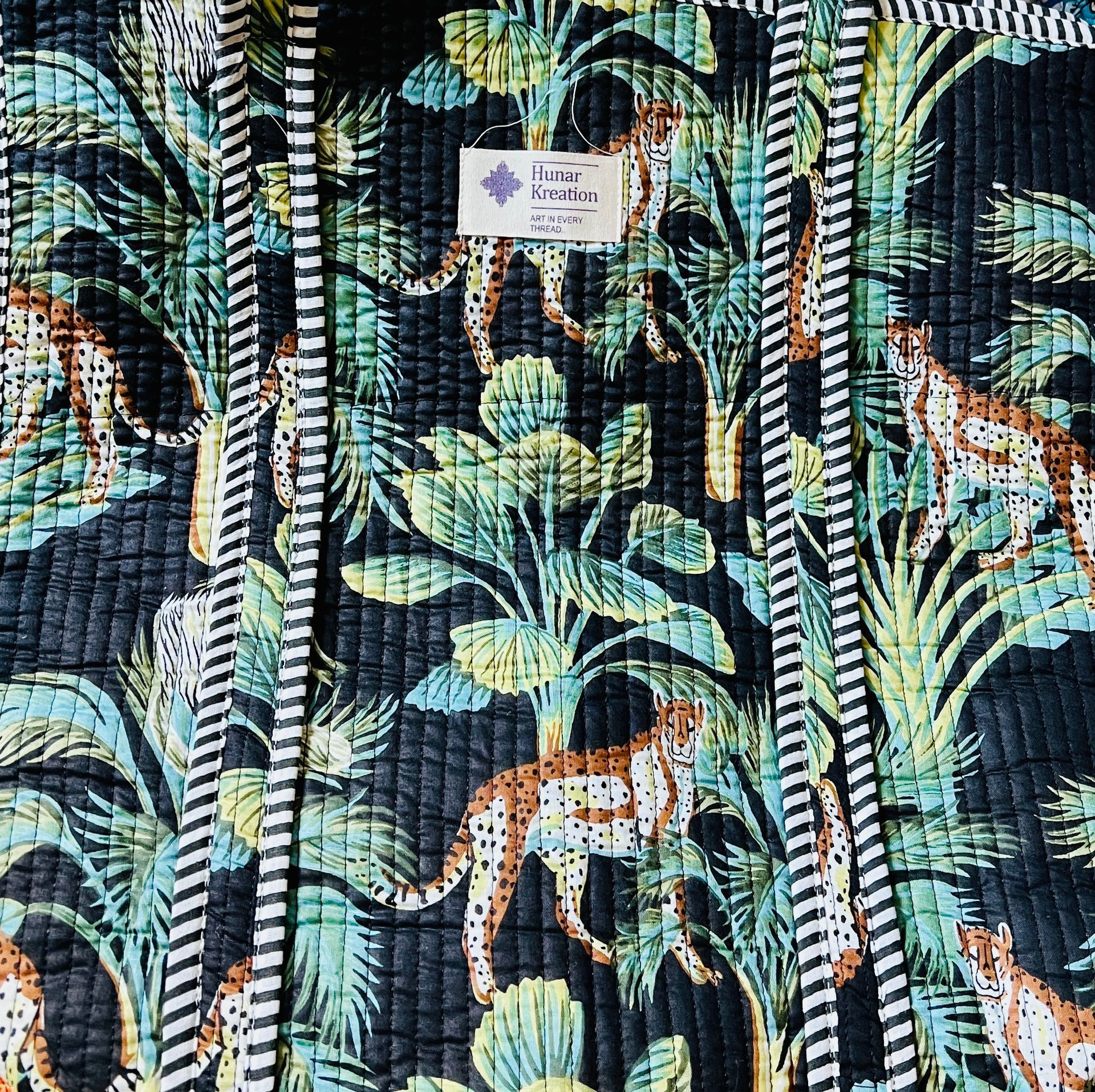 A close up of a quilt with leopards and palm trees on it.