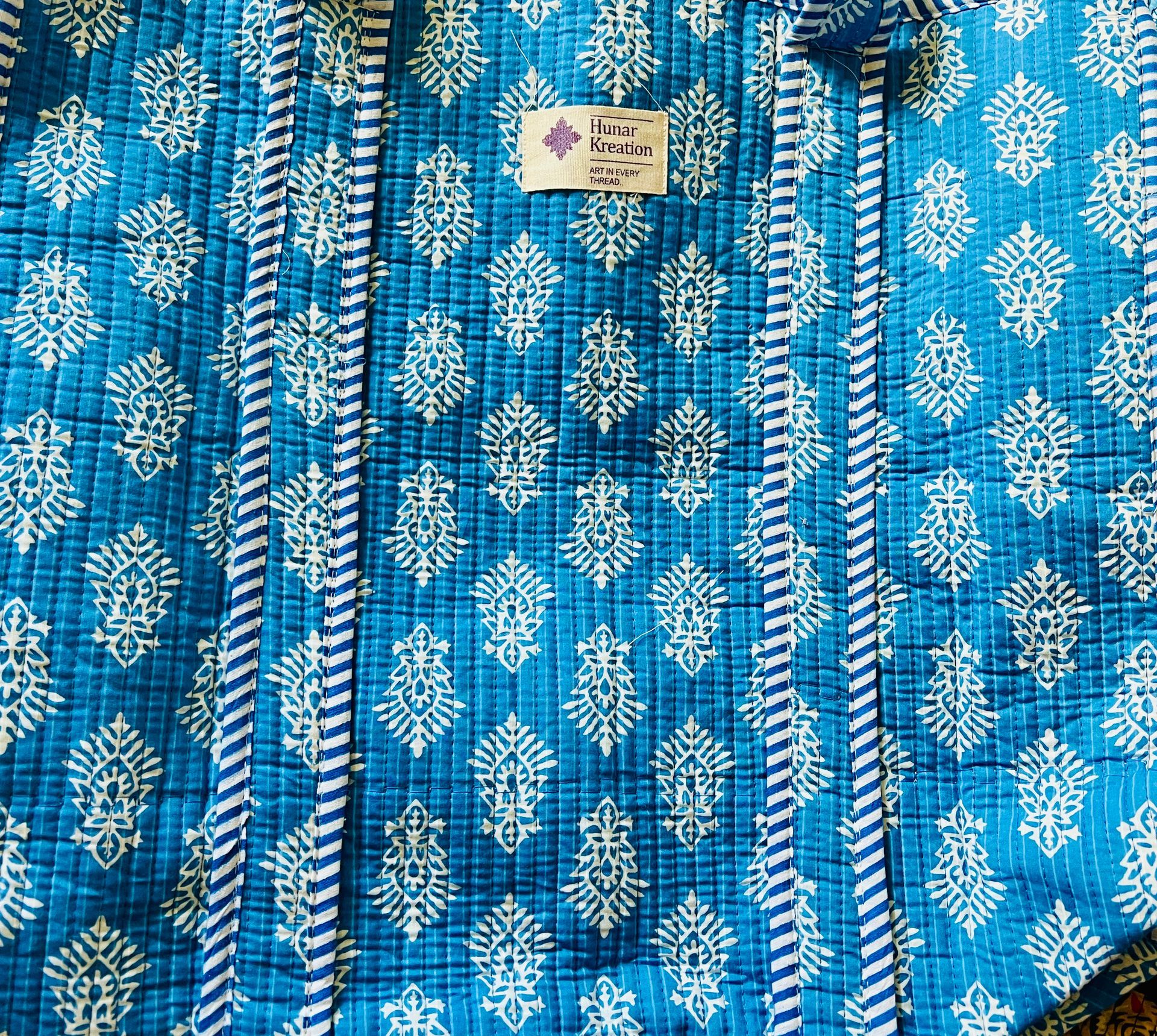 A close up of a blue and white quilt with a label on it