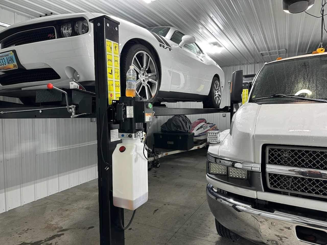 Black steel vehicle lift frame in an industrial garage bay with white walls and concrete floor