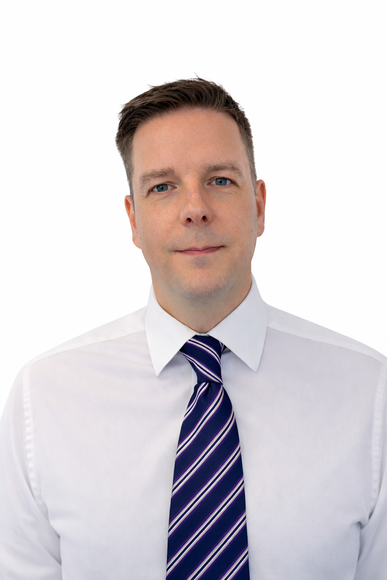 A person wearing a white button-down shirt and a navy blue striped tie, shown from the chest up against a white background.